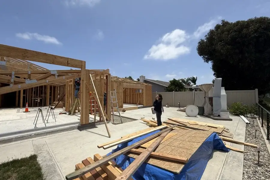 A designer reviewing drawings on site while framing goes up on a home under construction